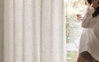 Woman enjoying a slow morning with coffee by the window, embodying soft life living with calm, cozy routines and natural light.