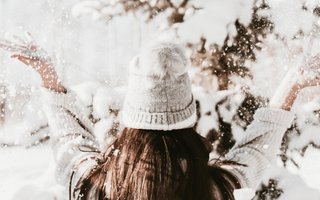 Woman in the snow with long brown hair and a beanie representing winter self discovery
