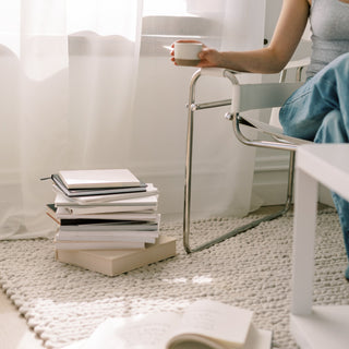 woman with coffee and stacks of books